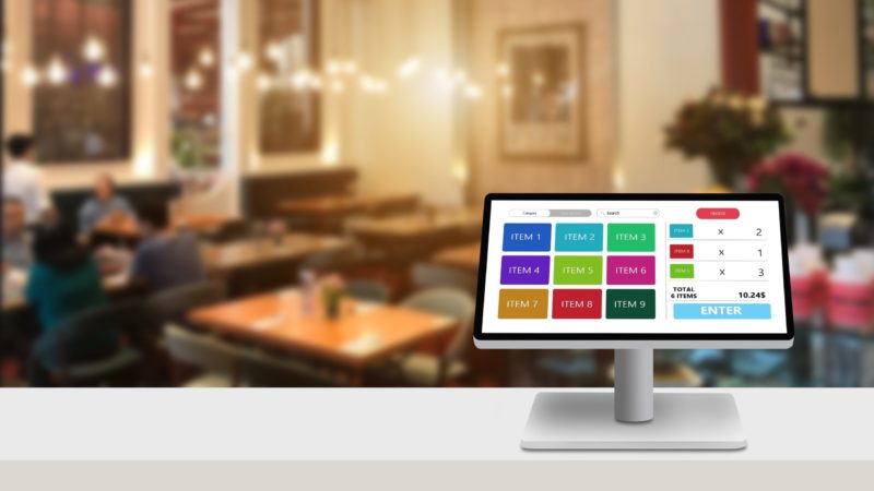 Registro de efectivo de pantalla táctil moderno en escritorio blanco con restaurante borroso como fondo